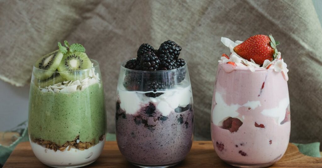 Delicious yogurt parfaits with kiwi, blackberries, and strawberries on a wooden board.